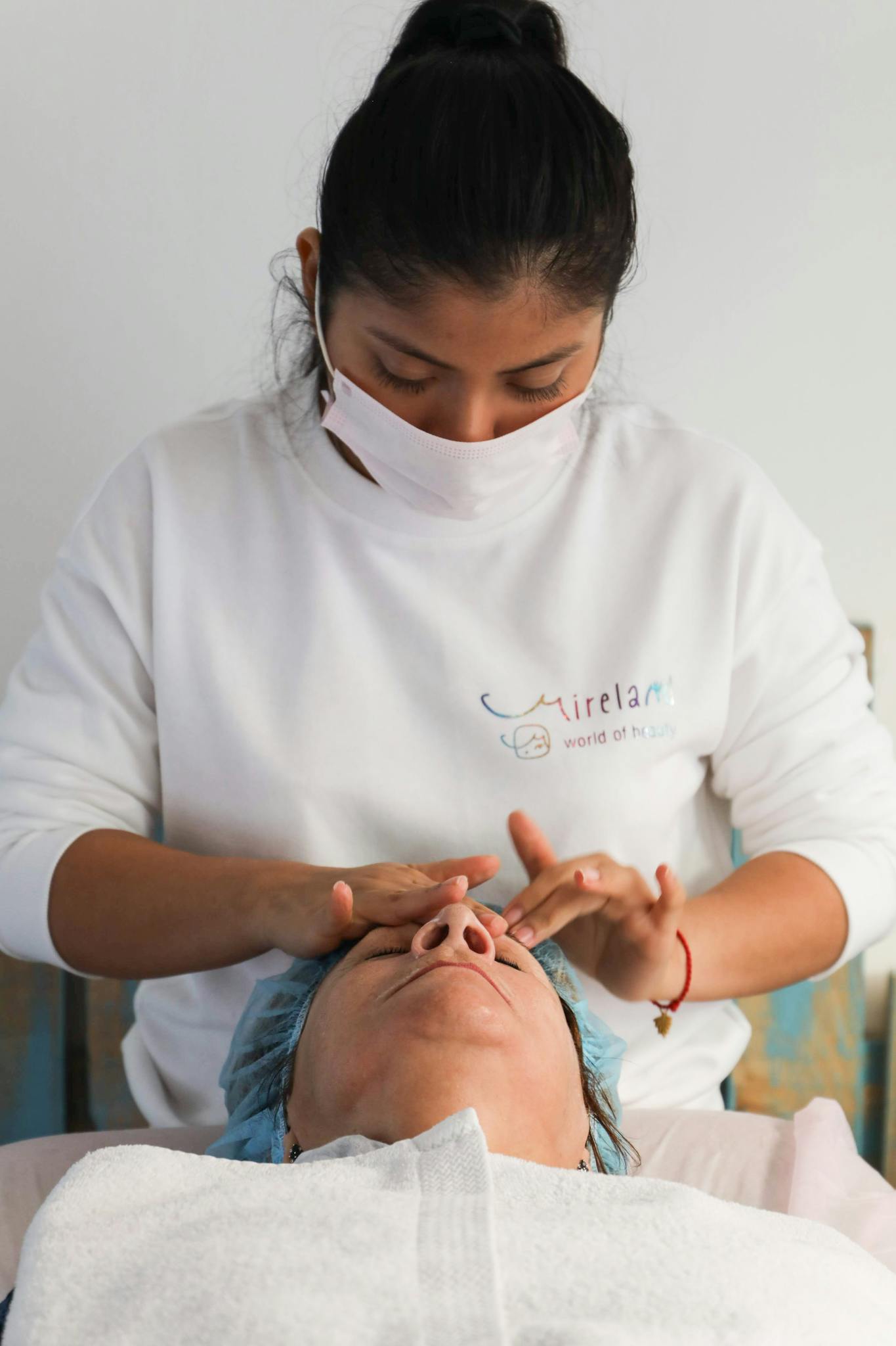 A woman receiving a facial massage by a therapist in a spa, promoting relaxation.